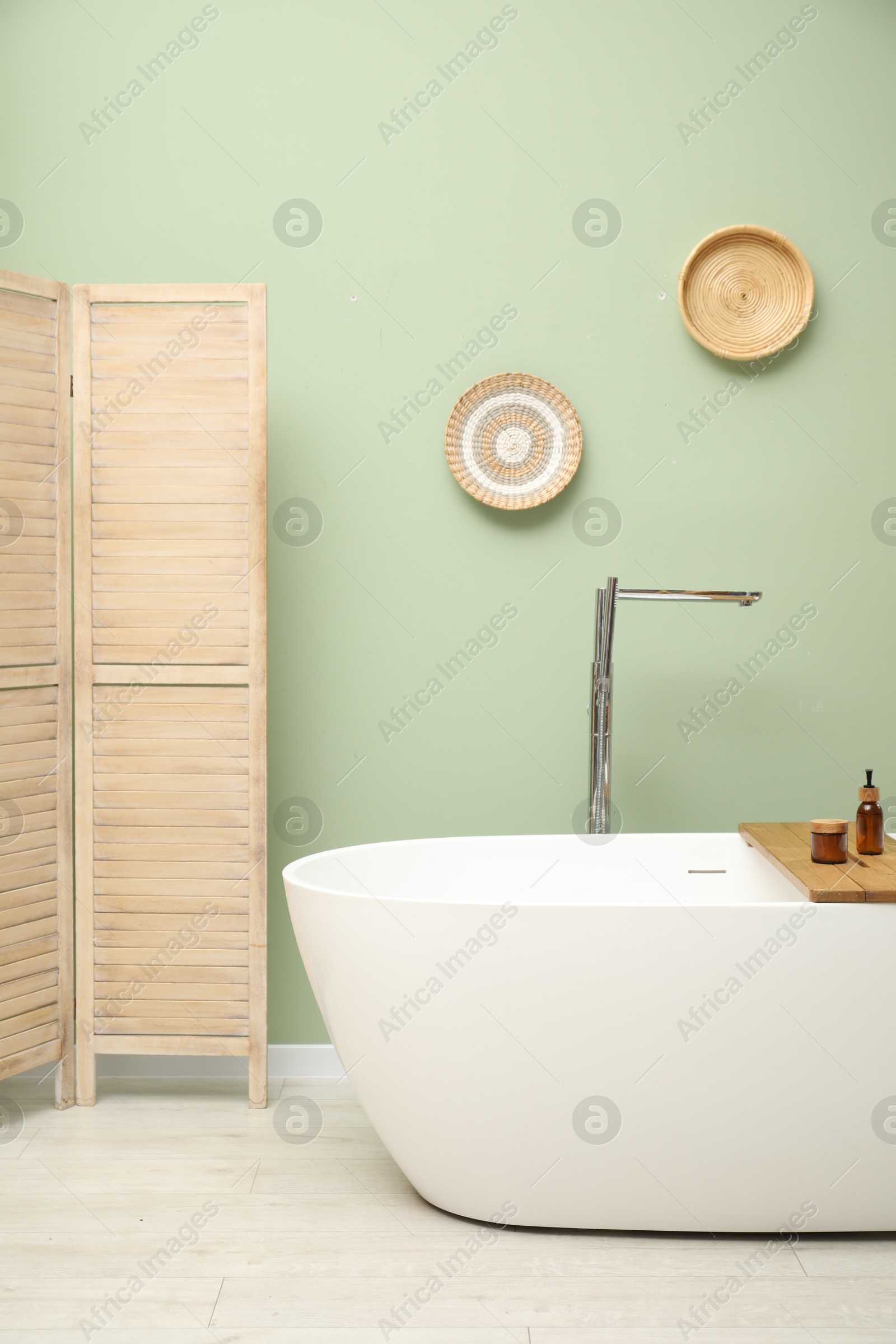 Photo of Stylish bathroom interior with folding screen and tub