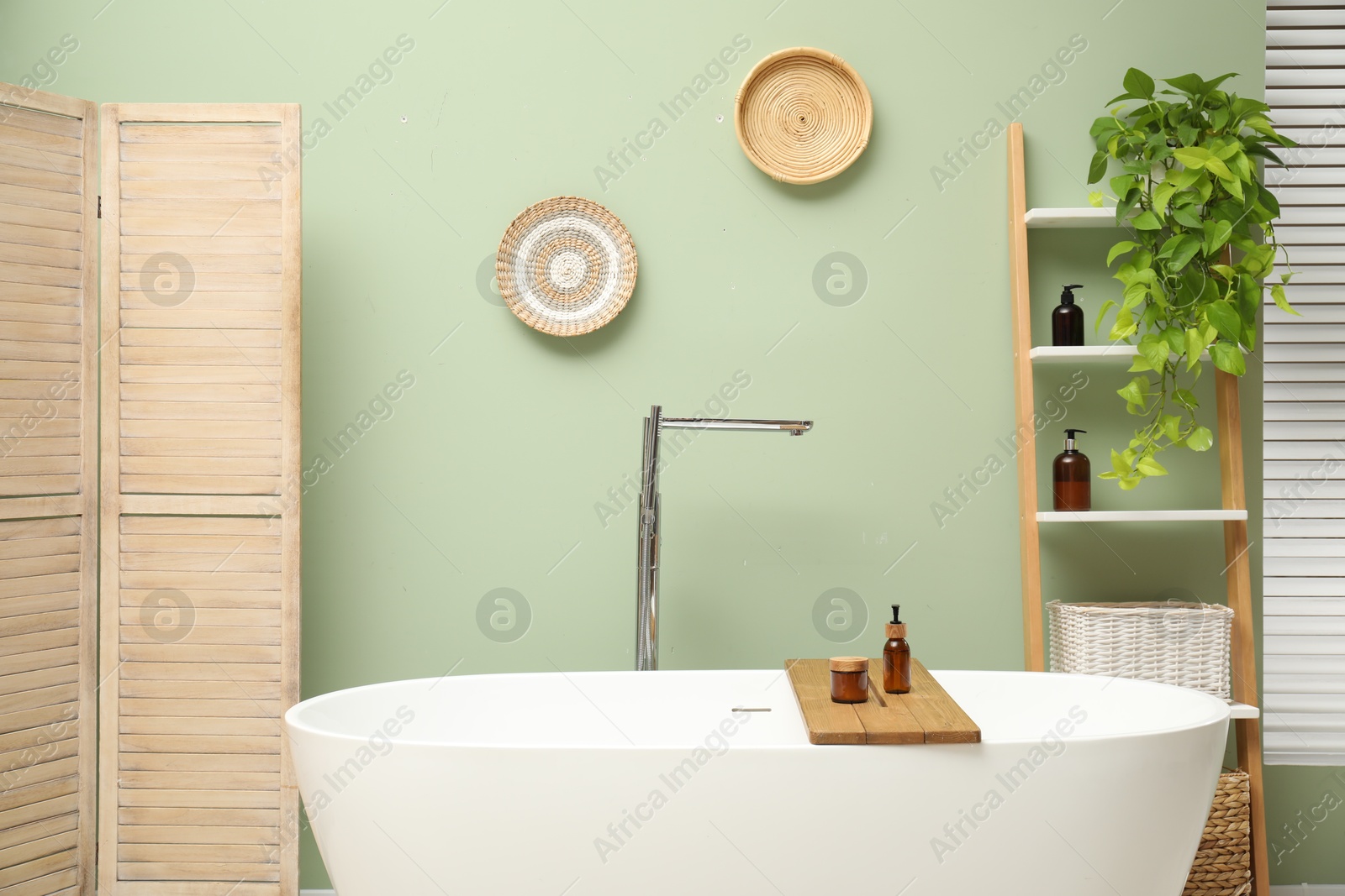 Photo of Stylish bathroom interior with folding screen and tub