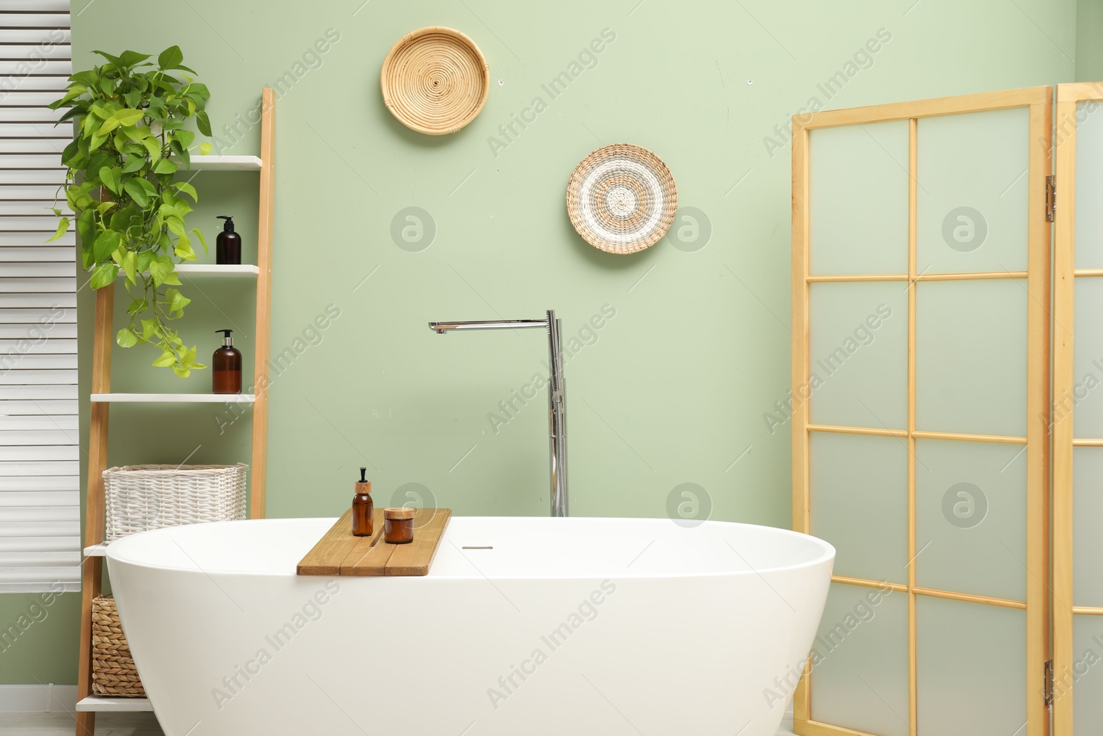 Photo of Stylish bathroom interior with folding screen and tub