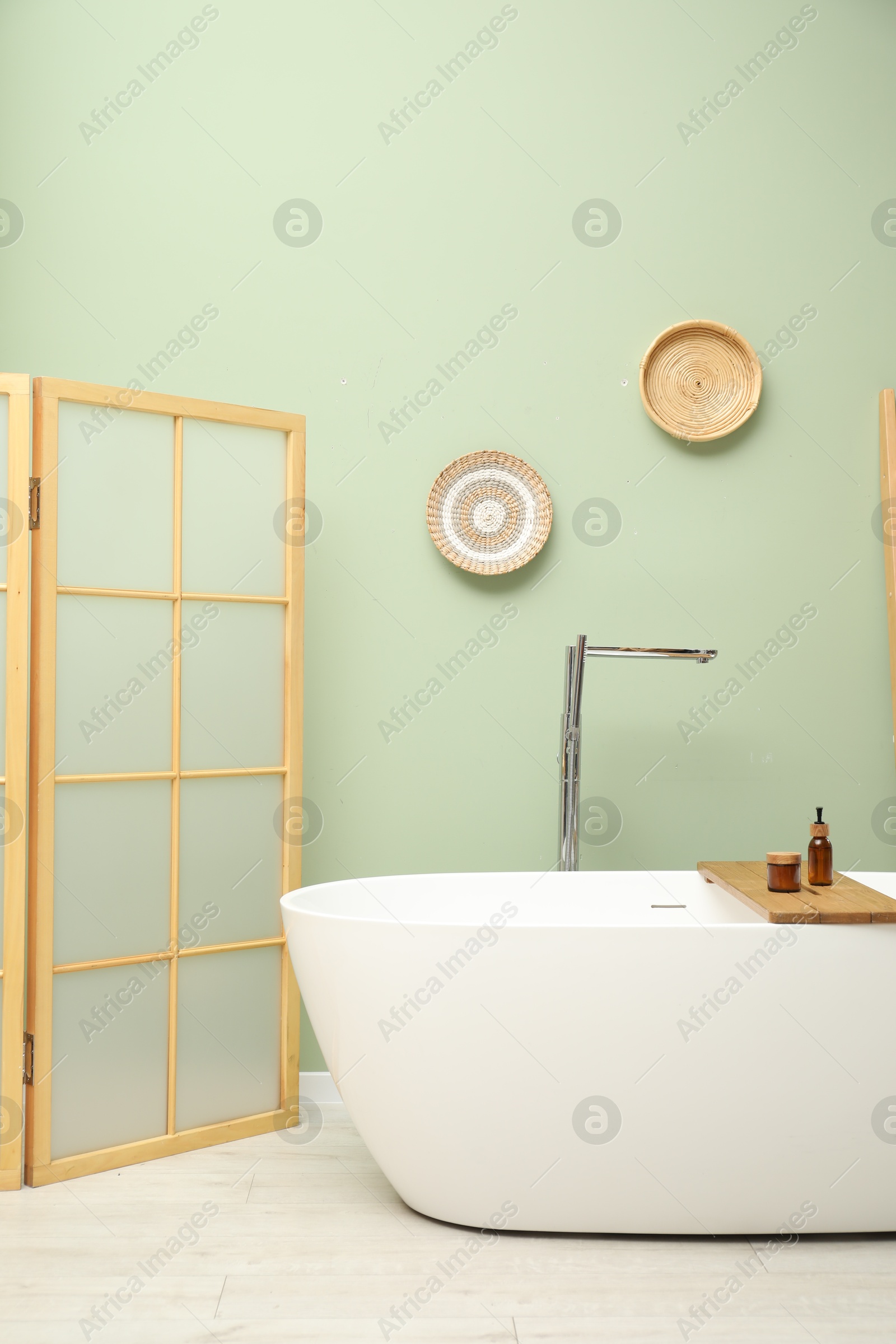 Photo of Stylish bathroom interior with folding screen and tub