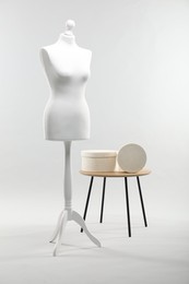 Mannequin and boxes on side table against light grey background. Fashion designer`s equipment