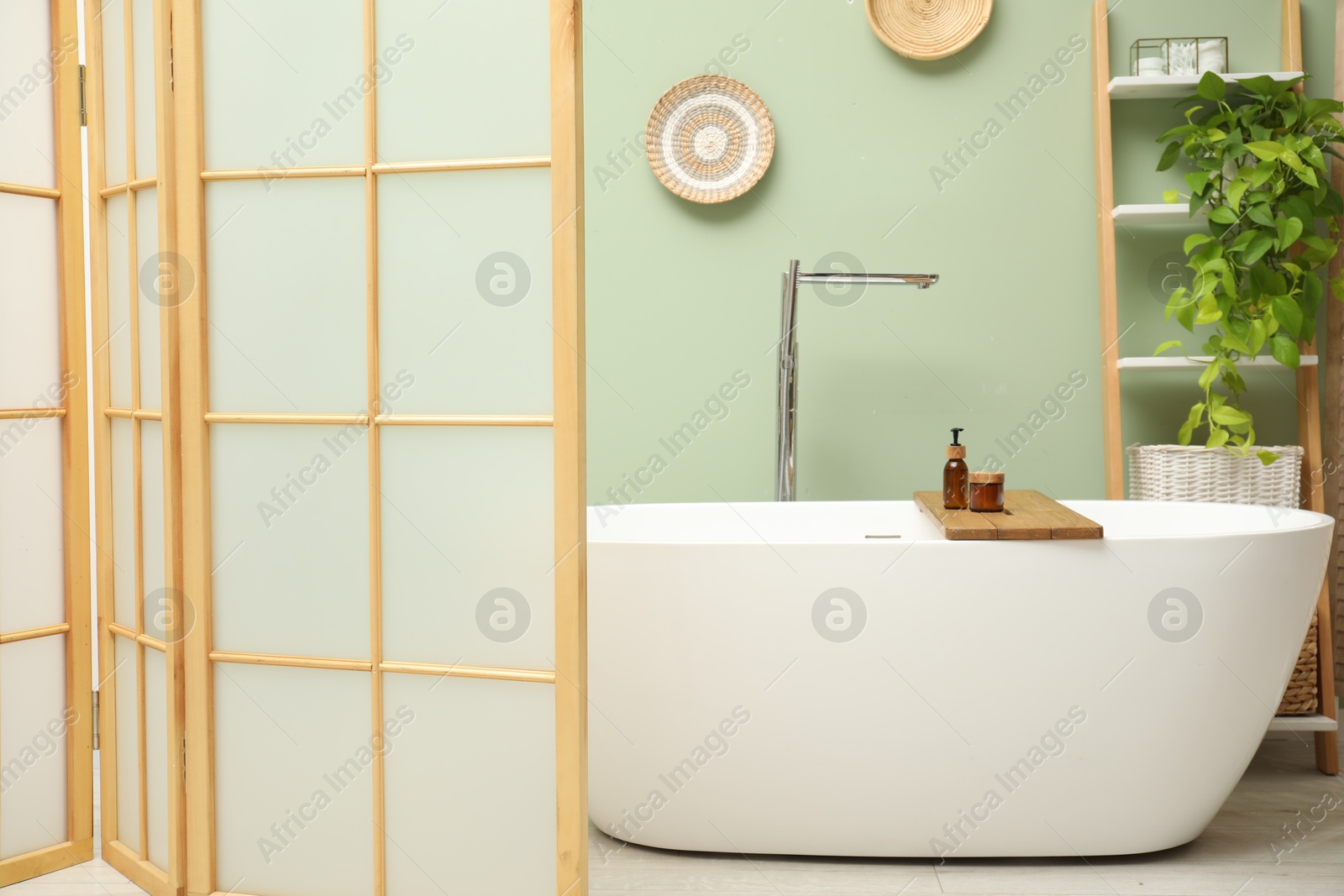 Photo of Stylish bathroom interior with folding screen and tub