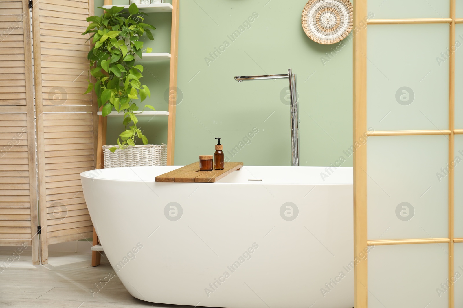 Photo of Stylish bathroom interior with folding screen and tub