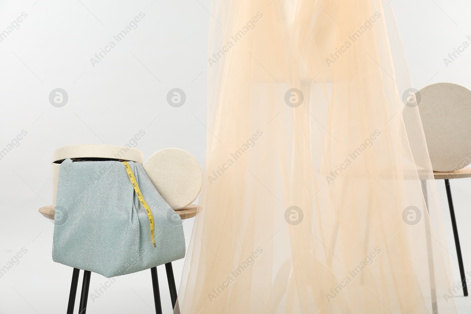 Photo of Mannequin with fabric and boxes on side tables against light grey background. Creating new outfit