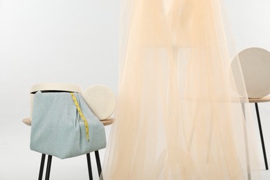 Photo of Mannequin with fabric and boxes on side tables against light grey background. Creating new outfit