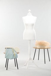 Photo of Mannequin with fabric and boxes on side tables against light grey background. Creating new outfit