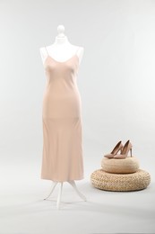 Photo of Mannequin with new stylish dress and high heels on light grey background