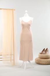 Mannequin with new stylish dress and high heels on light grey background