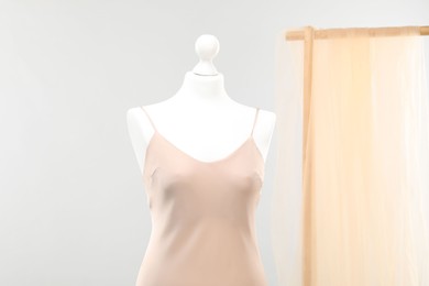 Photo of Mannequin with new stylish dress against light grey background