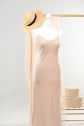 Photo of Mannequin with new stylish dress and wicker hat against light grey background