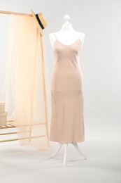 Mannequin with new stylish dress and wicker hat against light grey background