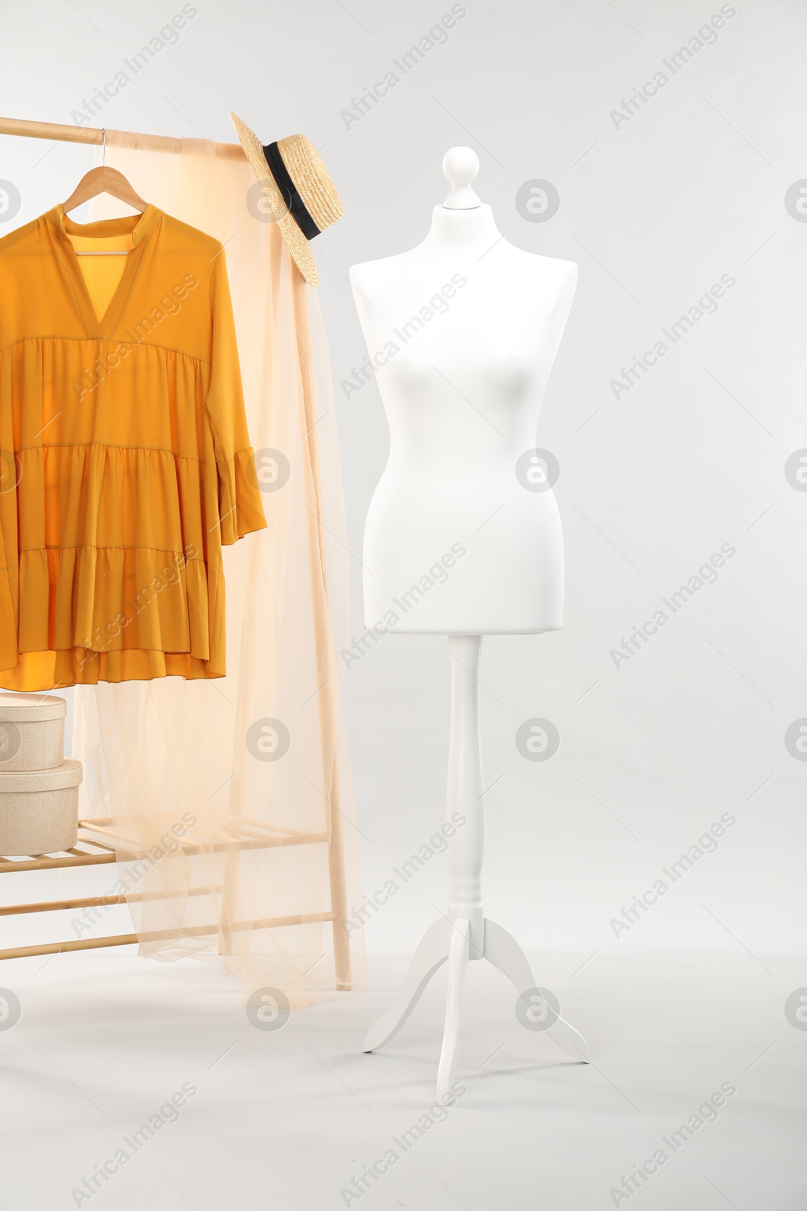 Photo of Mannequin, stylish dress and wicker hat on light grey background