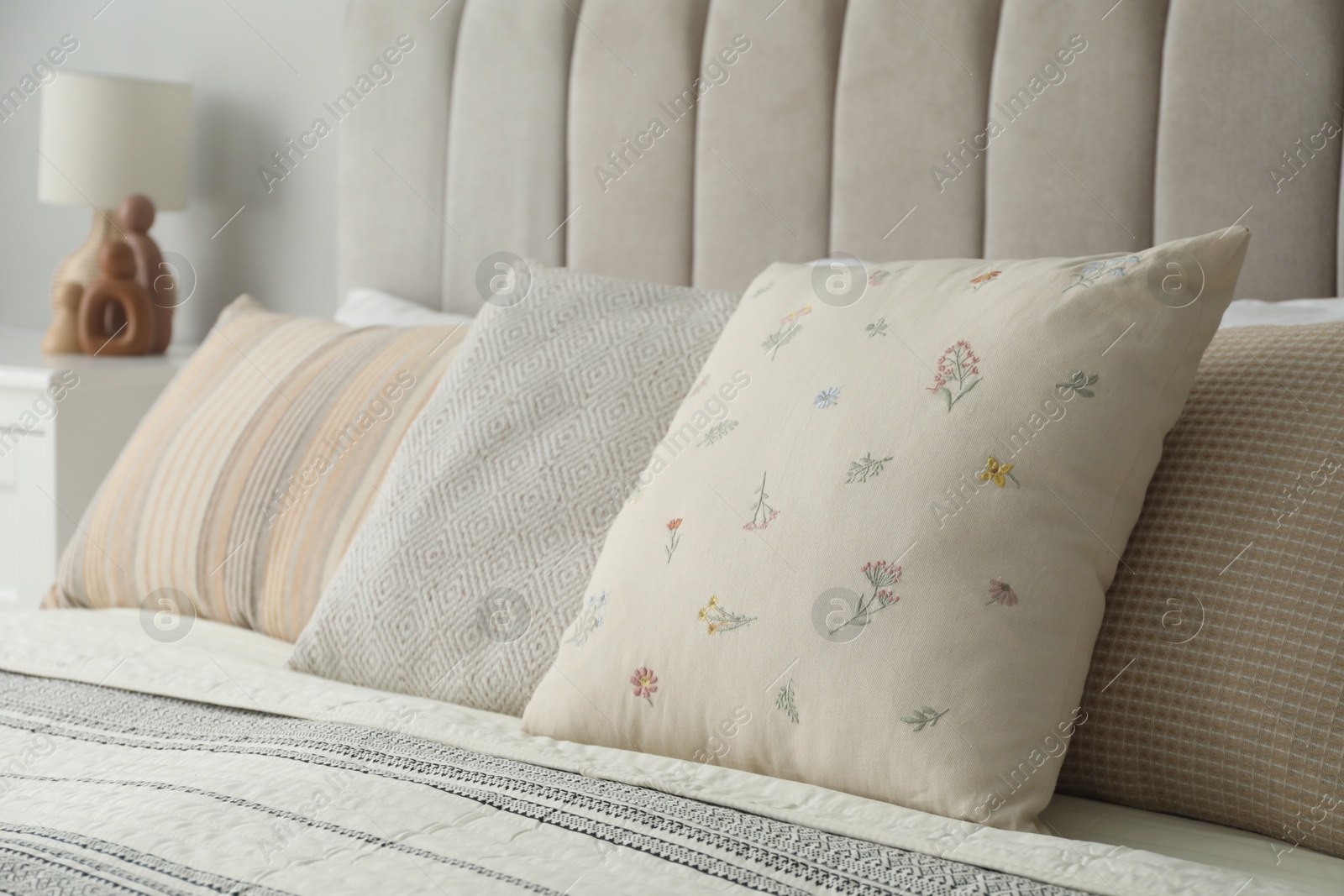 Photo of Different color pillows on bed in bedroom, closeup