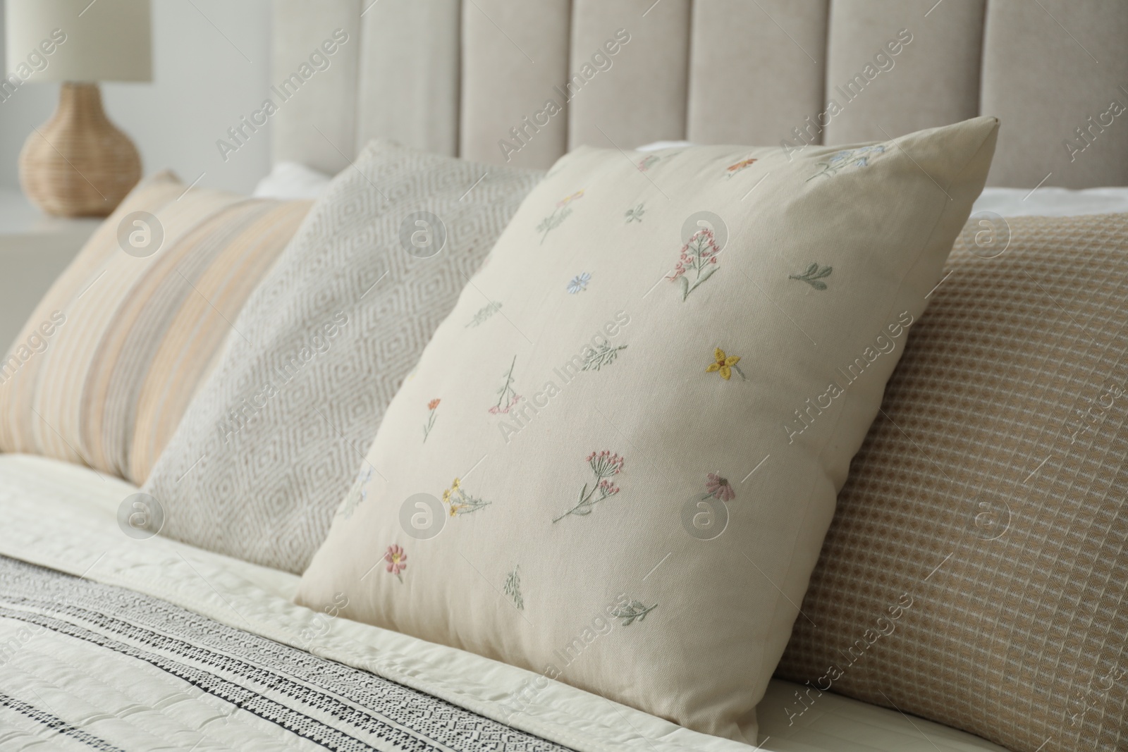 Photo of Different color pillows on bed in bedroom, closeup