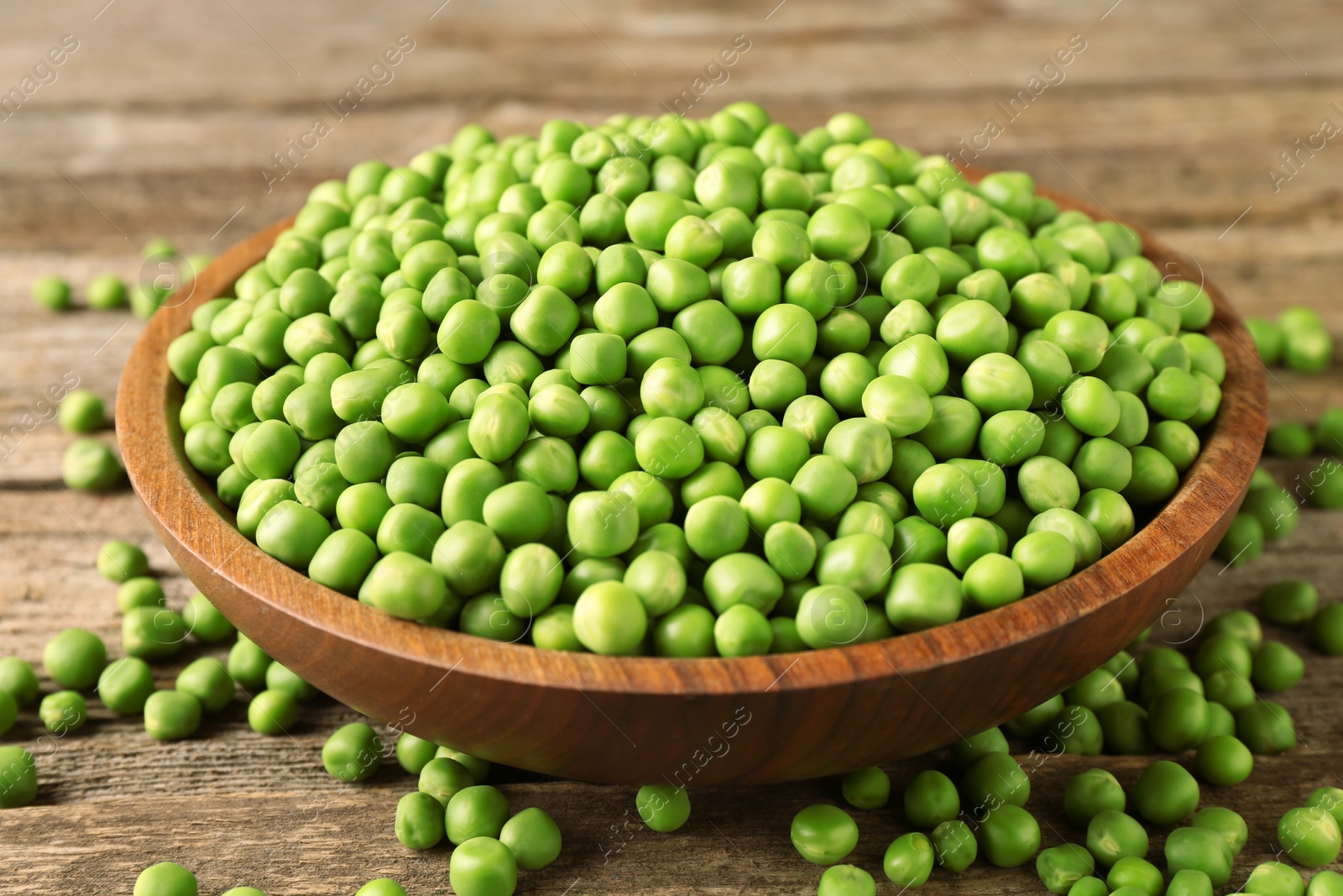 Photo of Fresh green peas in bowl on wooden table, closeup