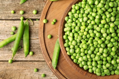 Photo of Fresh green peas in bowl and pods on wooden table, flat lay