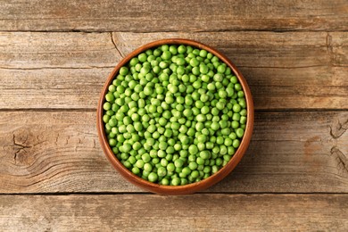 Photo of Fresh green peas in bowl on wooden table, top view