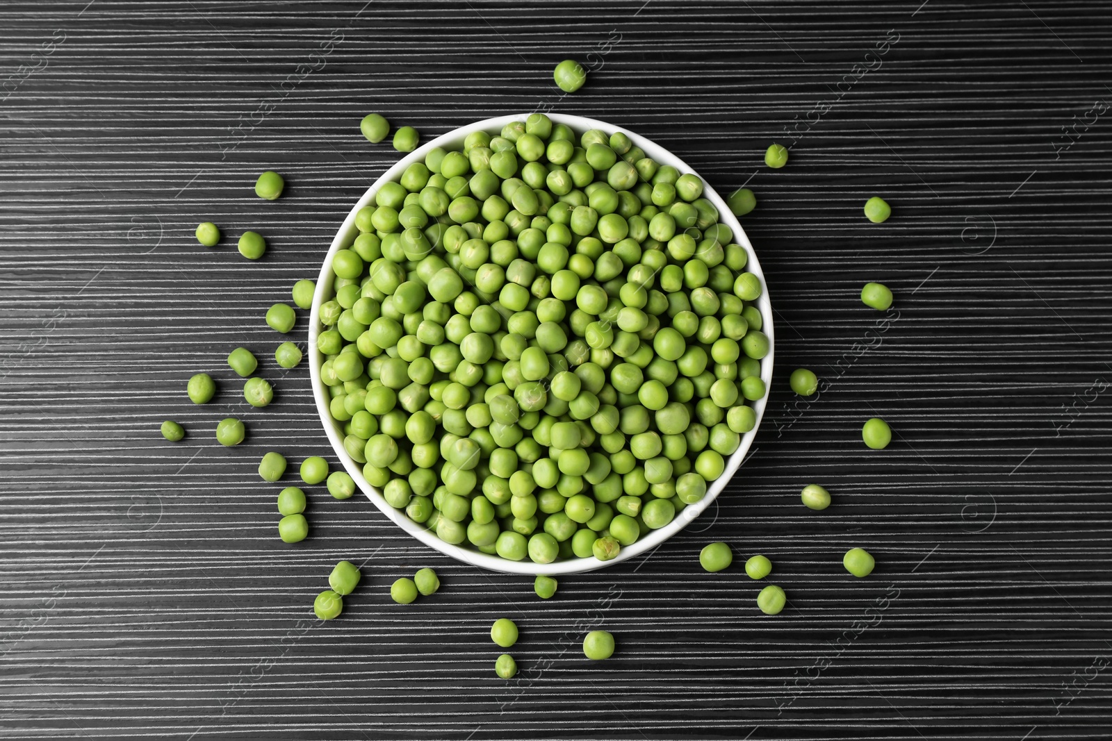 Photo of Fresh green peas on black wooden table, top view