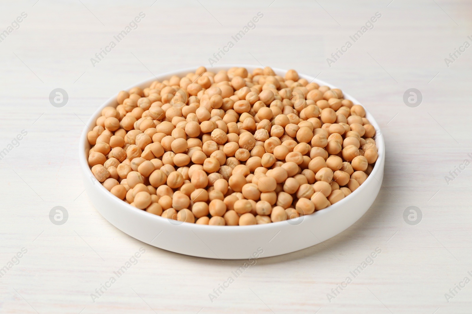 Photo of Dried peas on light wooden table, closeup