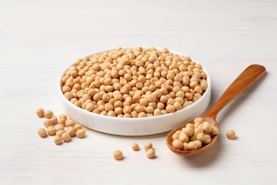 Photo of Dried peas, plate and spoon on light wooden table, closeup