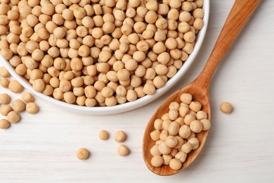 Dried peas, plate and spoon on light wooden table, flat lay