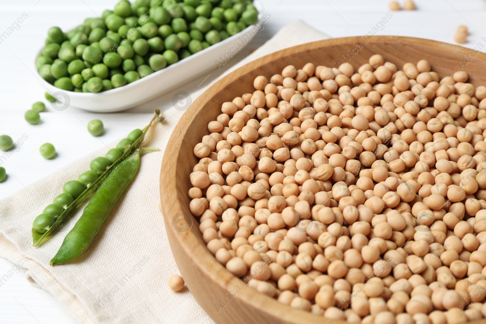 Photo of Dried peas and pods with fresh ones on white wooden table, closeup