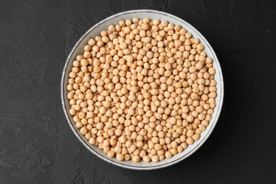 Photo of Dried peas in bowl on dark textured table, top view