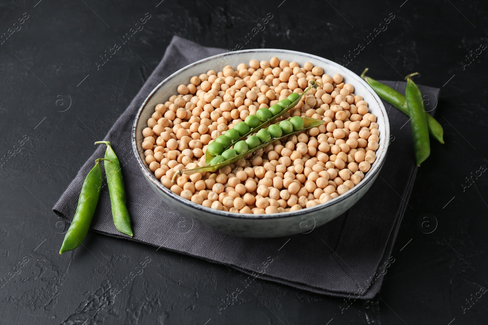 Photo of Dried peas and pods with fresh ones on dark textured table, closeup