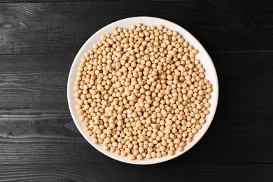 Dried peas in bowl on black wooden table, top view