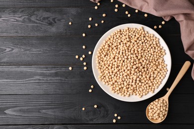 Dried peas in bowl and spoon on black wooden table, flat lay. Space for text