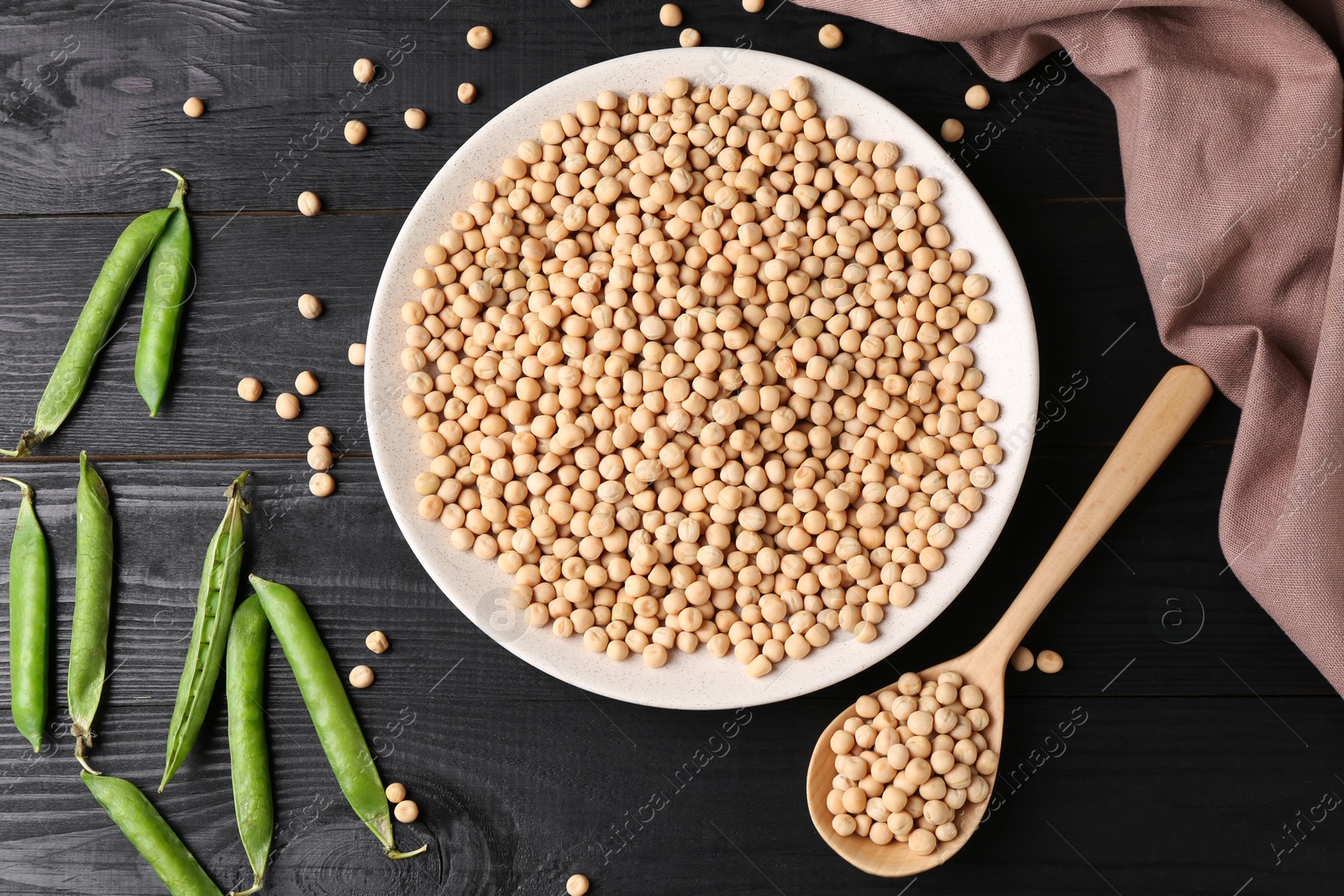 Photo of Dried peas and pods with fresh ones on black wooden table, flat lay