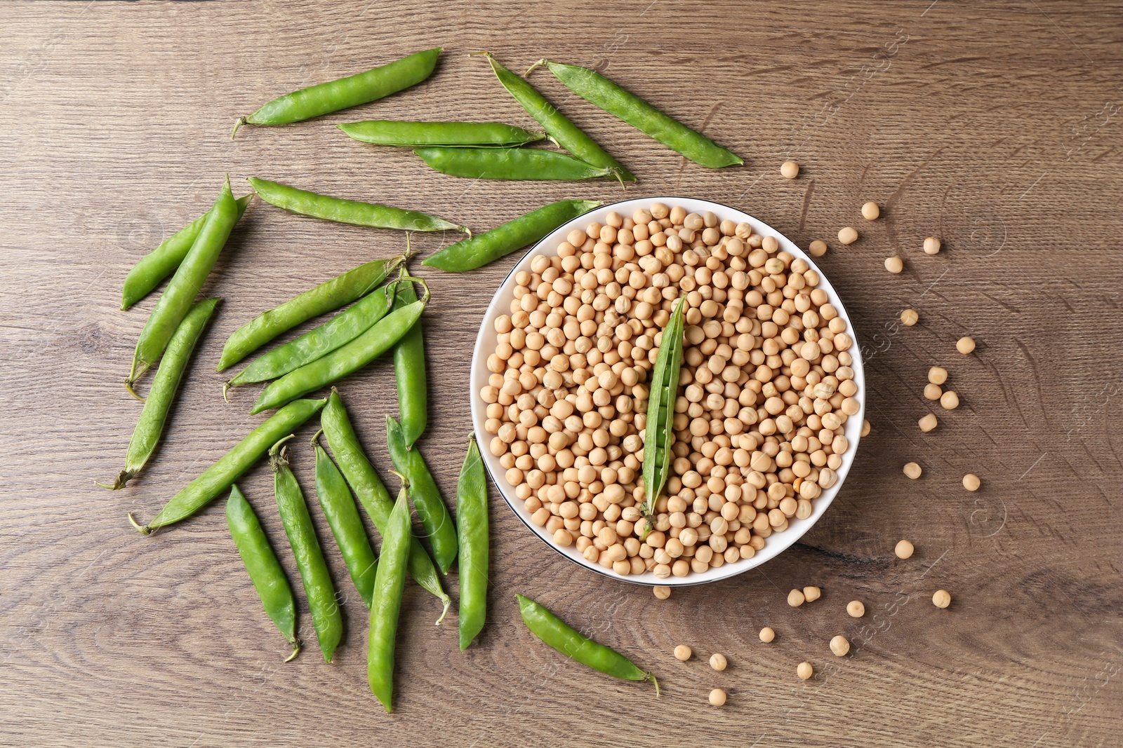 Photo of Dried peas and pods with fresh ones on wooden table, flat lay