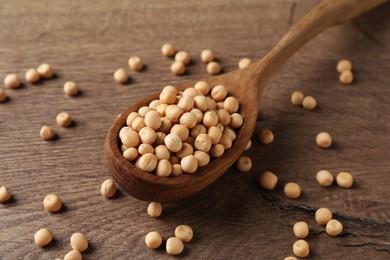 Spoon with dried peas on wooden table, closeup