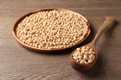 Photo of Dried peas, plate and spoon on wooden table, closeup