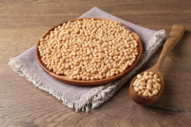 Dried peas, plate and spoon on wooden table, closeup