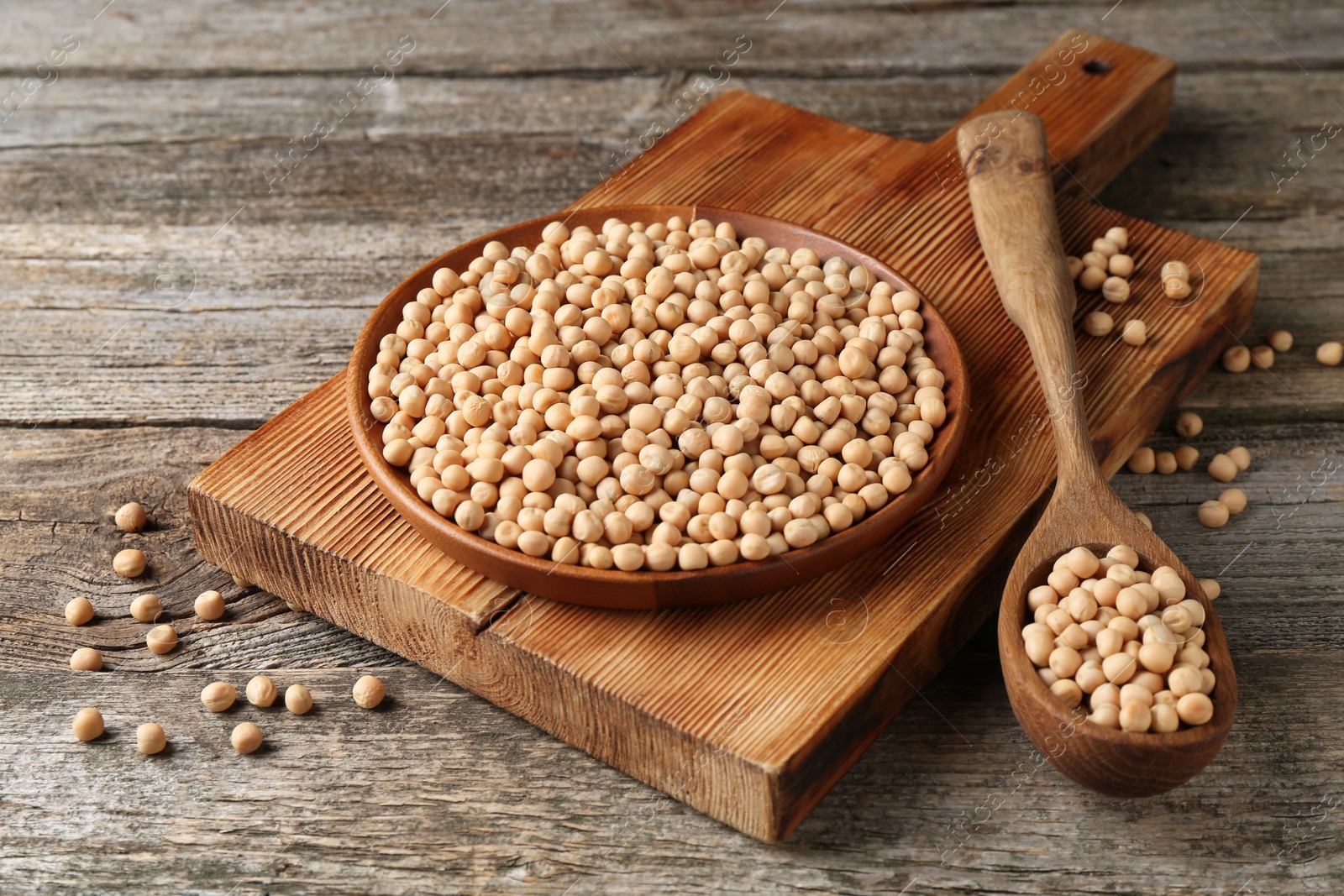 Dried peas, plate, board and spoon on wooden table, closeup Photo of Dried peas, plate, board and spoon on wooden table, closeup