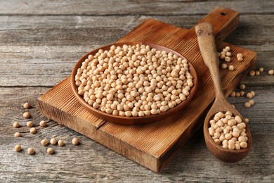 Photo of Dried peas, plate, board and spoon on wooden table, closeup