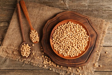 Photo of Dried peas, plate and spoons on wooden table, top view