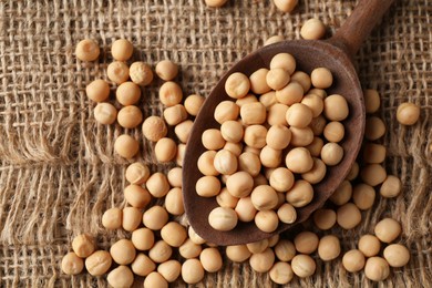 Photo of Spoon with dried peas on burlap fabric, top view