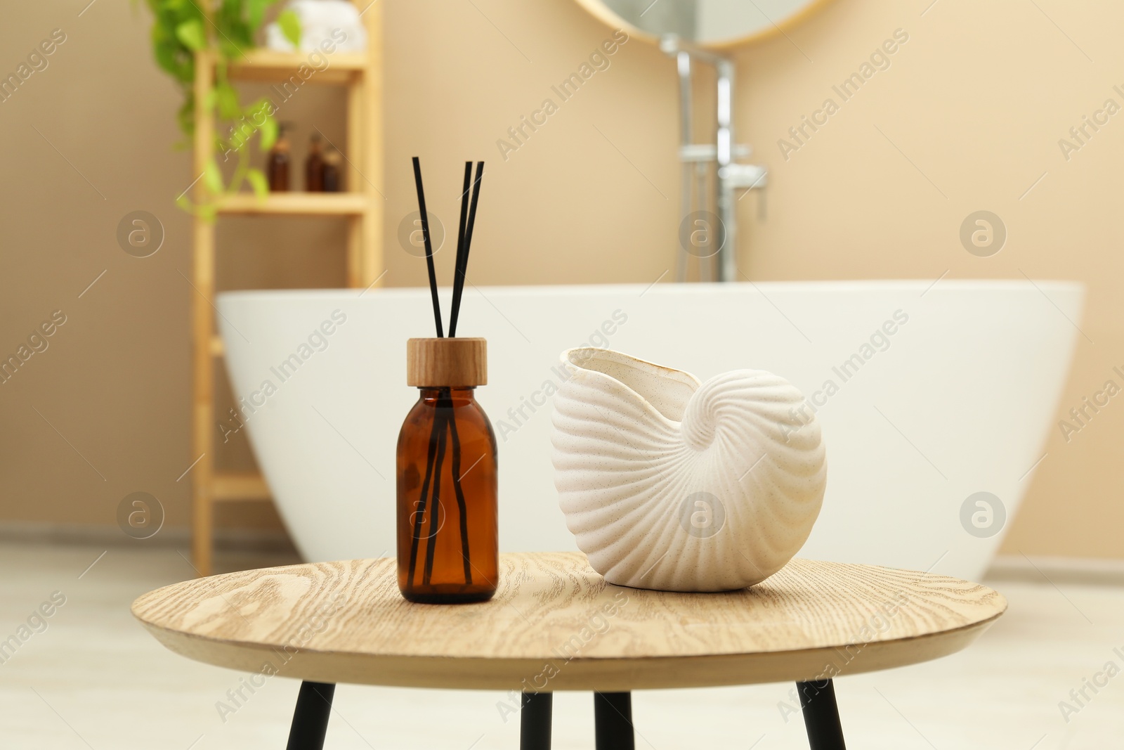 Photo of Reed diffuser and beautiful shell shaped vase on table in bathroom