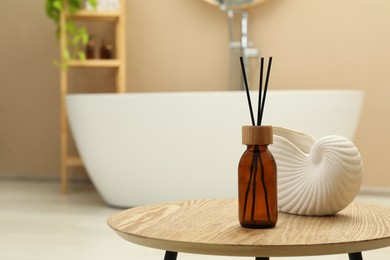 Photo of Reed diffuser and beautiful shell shaped vase on table in bathroom. Space for text