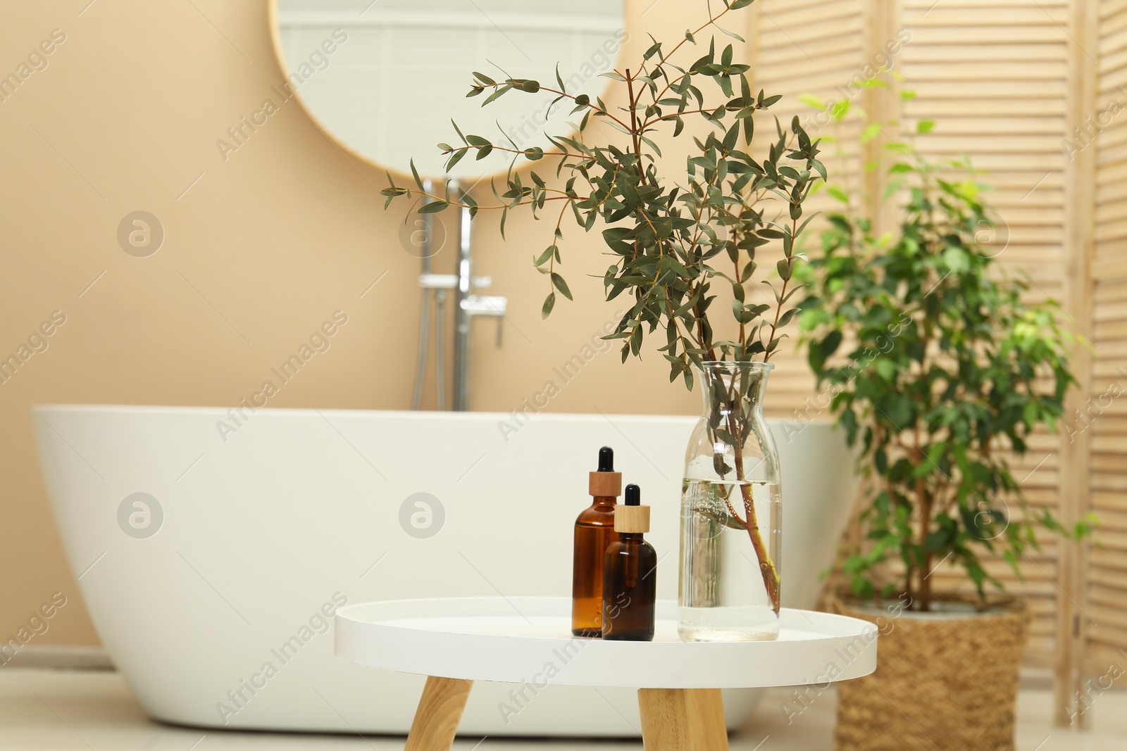 Photo of Personal care products and glass vase on table in bathroom