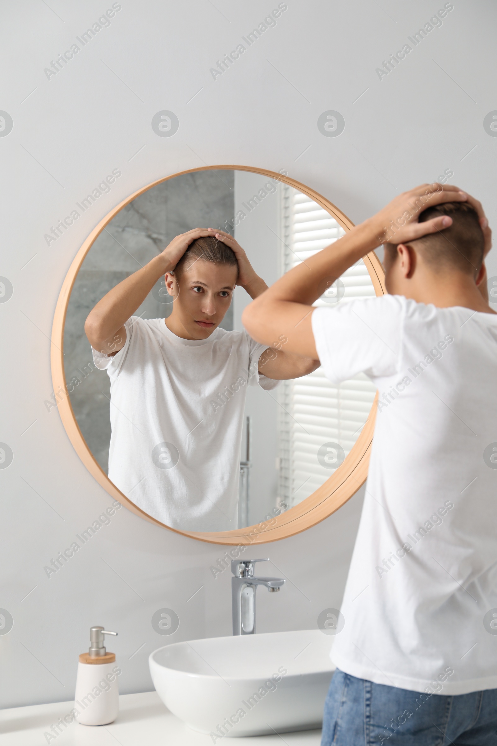 Photo of Handsome man looking at mirror in bathroom