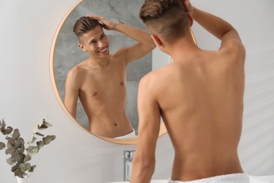 Photo of Handsome man looking at mirror in bathroom