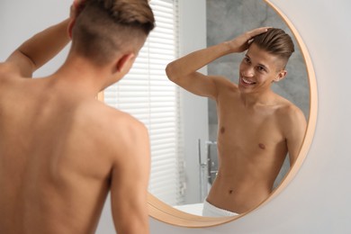 Handsome man looking at mirror in bathroom