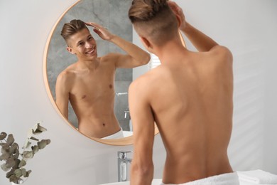 Handsome man looking at mirror in bathroom