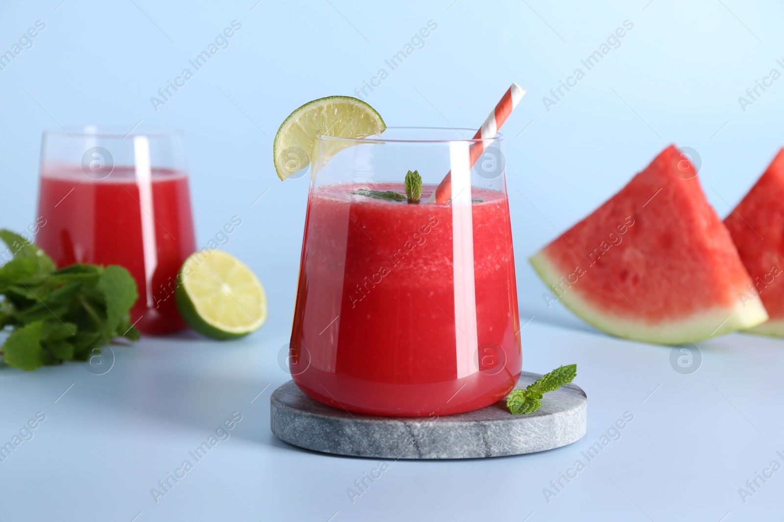 Photo of Tasty watermelon drink in glasses, fresh fruits and mint on light blue background