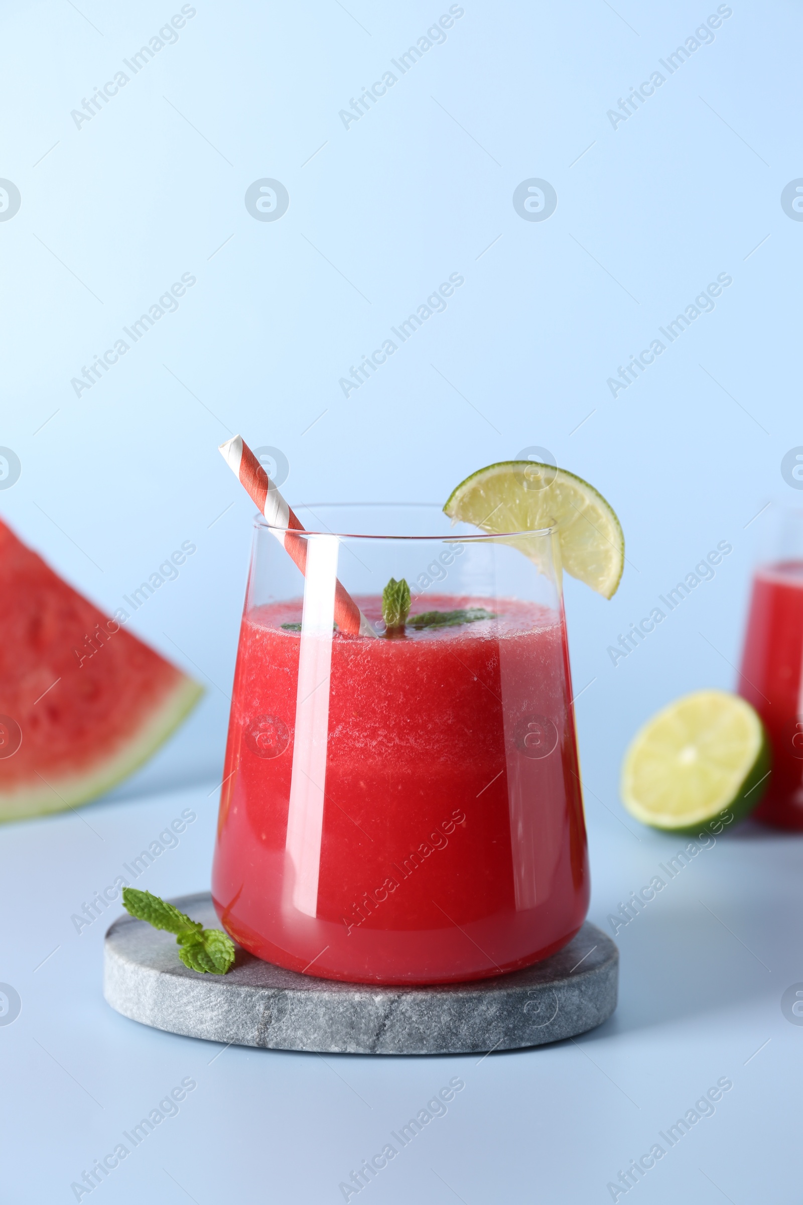 Photo of Tasty watermelon drink in glass, mint and fresh fruit on light blue background