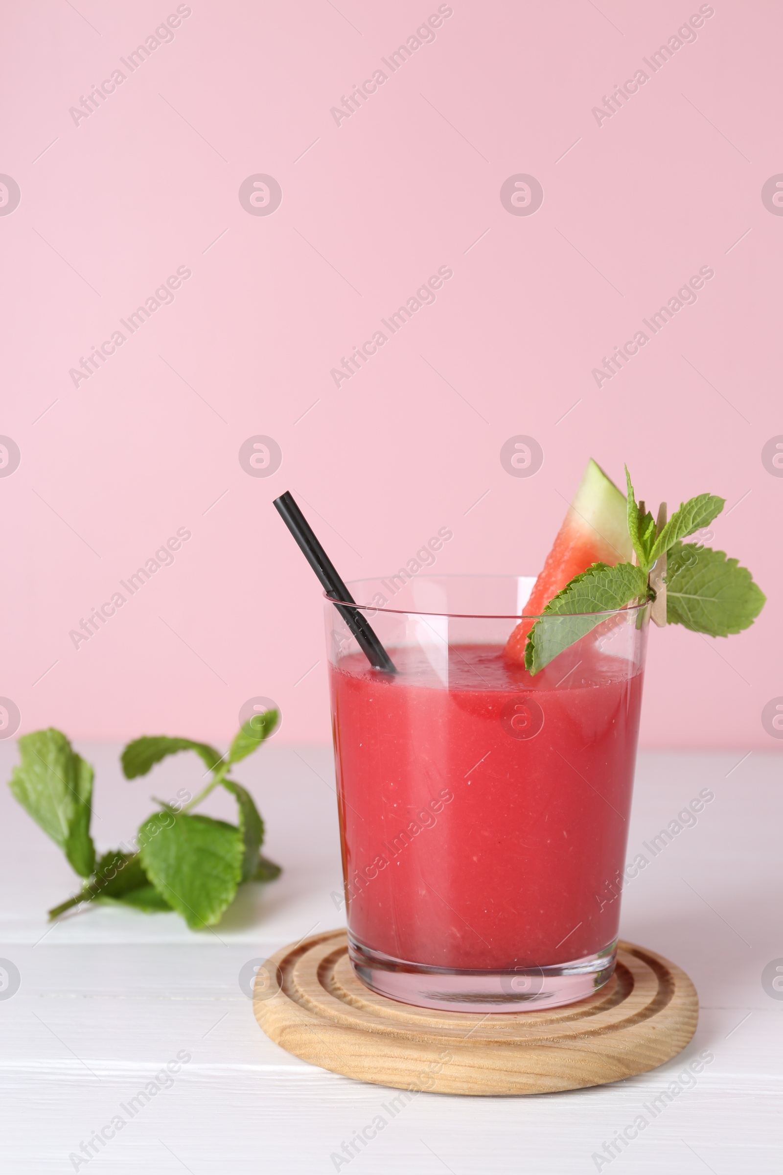 Photo of Tasty watermelon drink in glass and mint on white wooden table