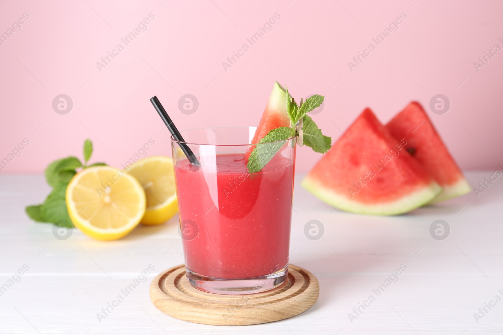 Photo of Tasty watermelon drink in glass, mint and fresh fruits on white wooden table